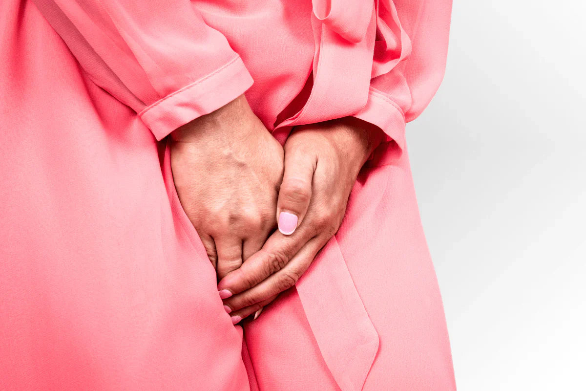 the midsection of a person dressed in pink with their hands covering their vagina