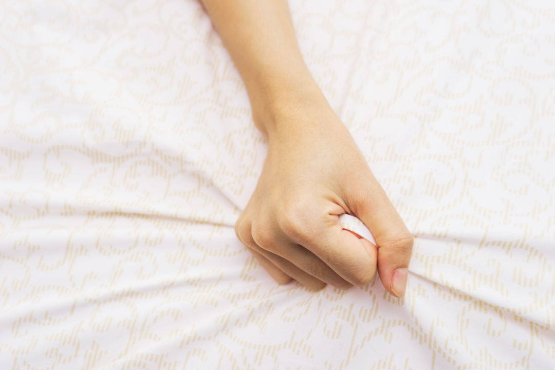 A hand grasps a bedsheet