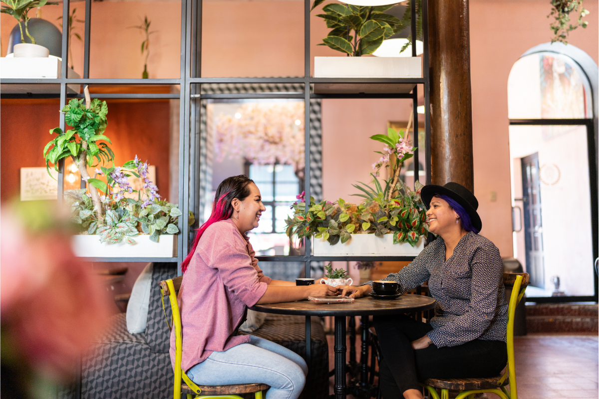 Two people on a date at a cafe in conversation, smiling and touching hands. 