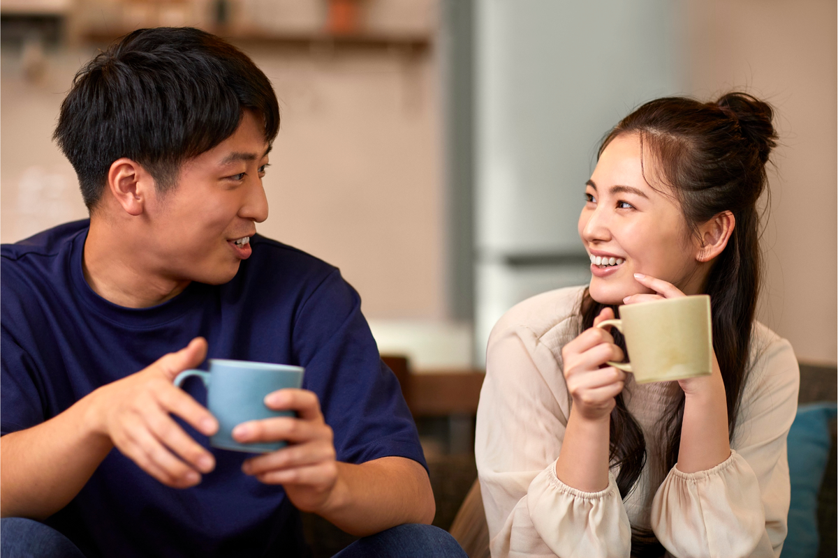 A couple sits on a couch smiling and talking 